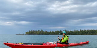 woman poses while sea kayaking in rainy weather