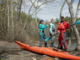 man and women put on drysuits while preparing for a kayaking excursion