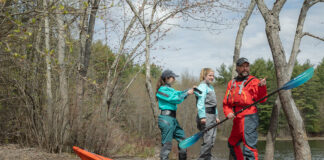 man and women put on drysuits while preparing for a kayaking excursion