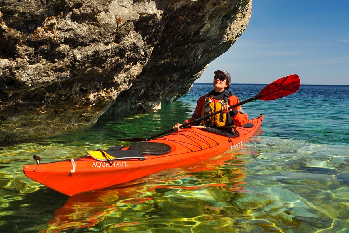 Kaydi Pyette sea kayaks on the Great Lakes while wearing the Kokatat Guide life jacket