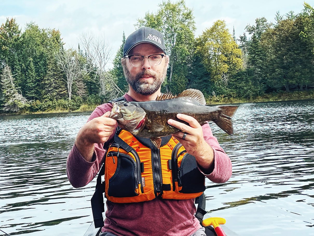 Paddling Magazine art director Michael Hewis poses with a fish while wearing the Stohlquist Keeper PFD