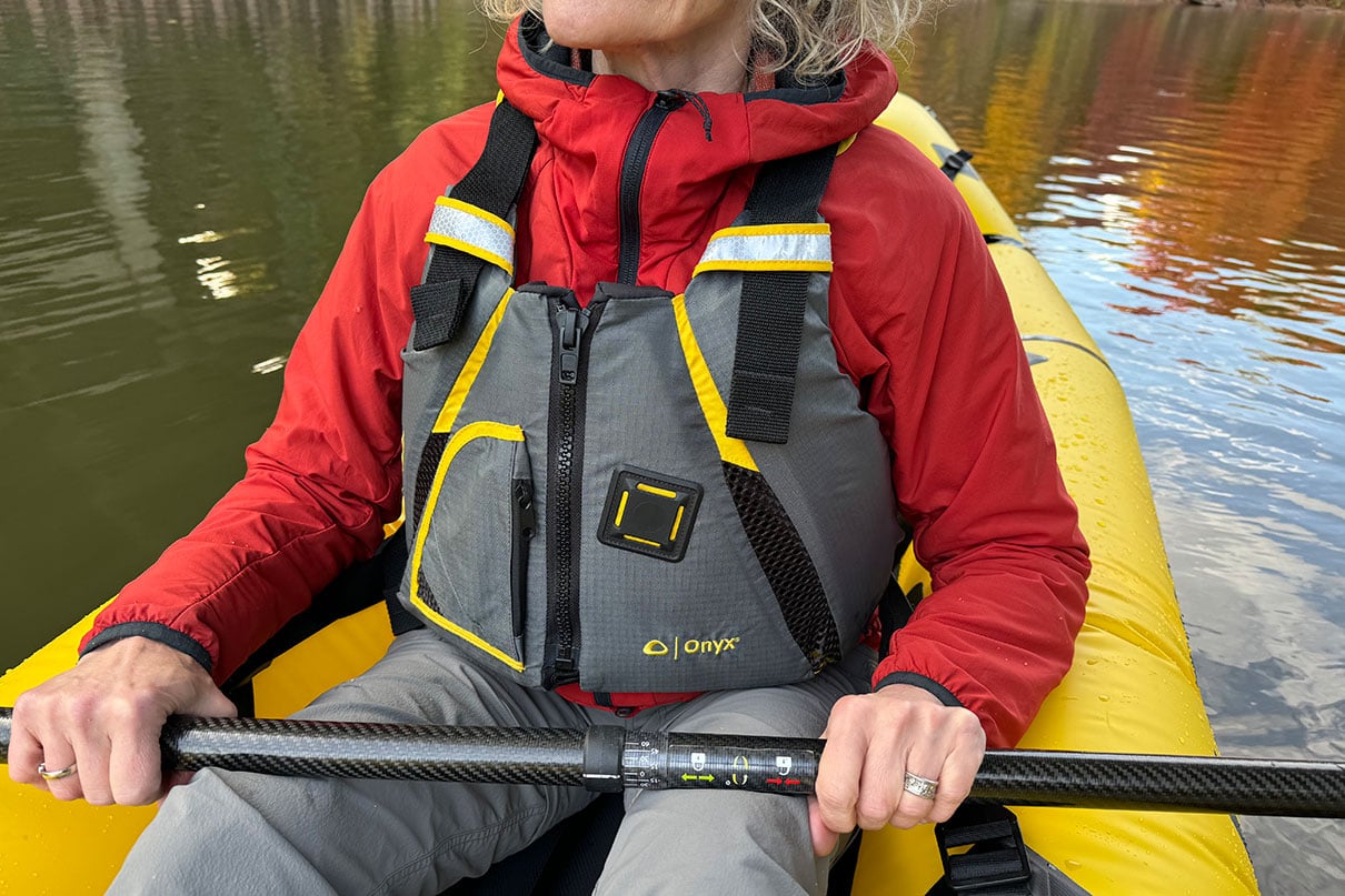 woman poses a yellow packraft while wearing the ONYX MoveVent life jacket