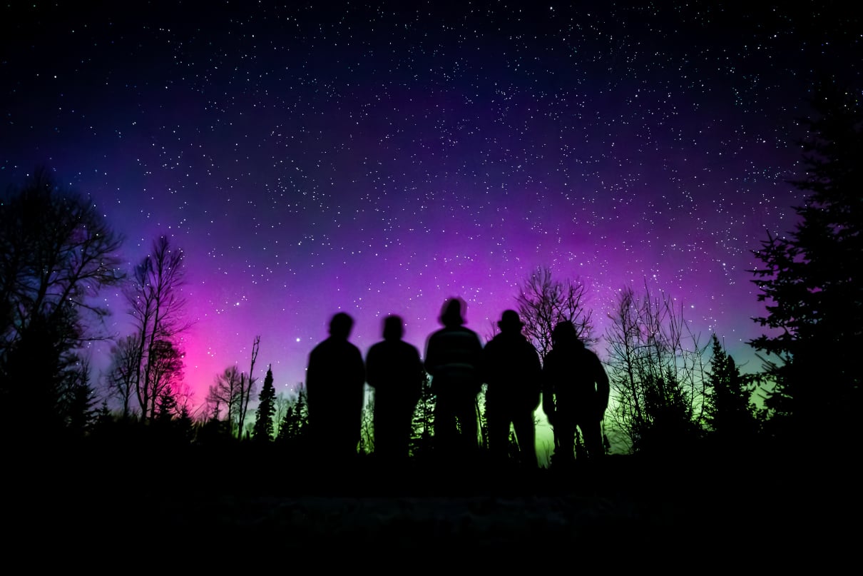 Group standing under the aurora borealis.