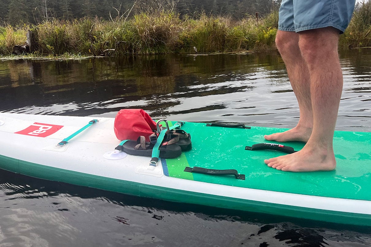 man's feet standing on a standup paddleboard