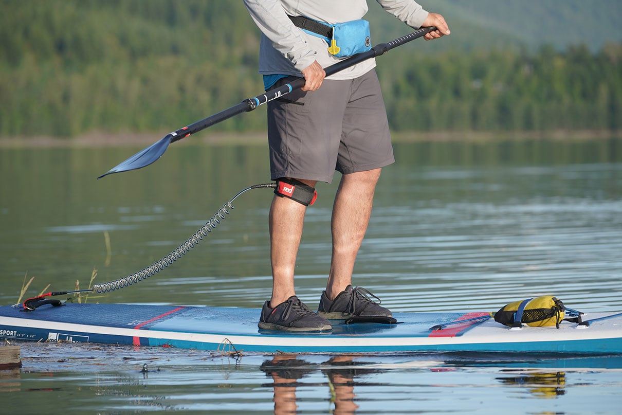 chest-down shot of a man paddleboarding while wearing an inflatable belt-style PFD