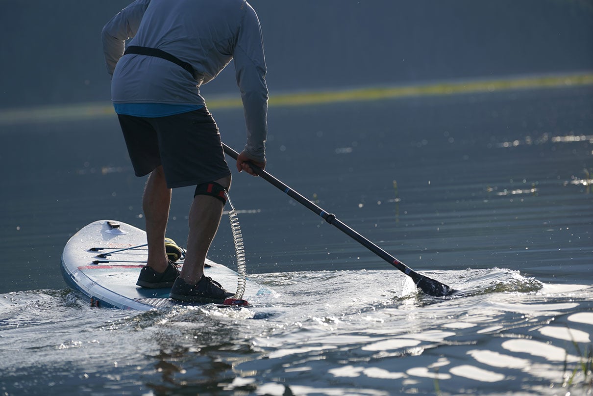 person uses a reverse stroke to turn while paddleboarding