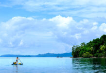 a woman paddleboards in an idyllic tropical location in Indonesia