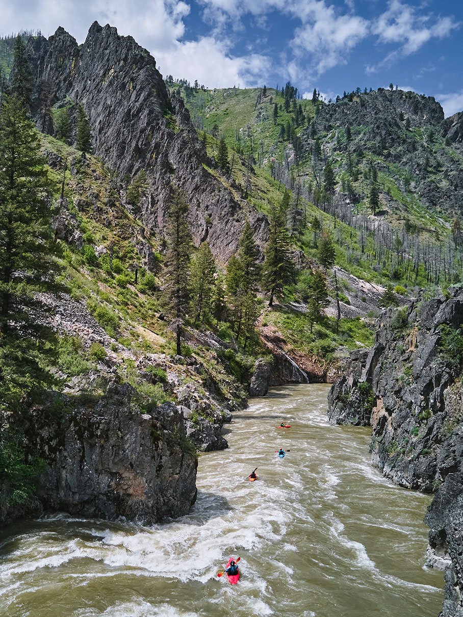 a group of whitewater paddlers kayaking down a river with rocky ridges all around