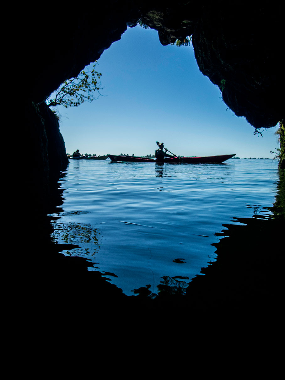 sea kayaker paddling shot from within a cave or overhang