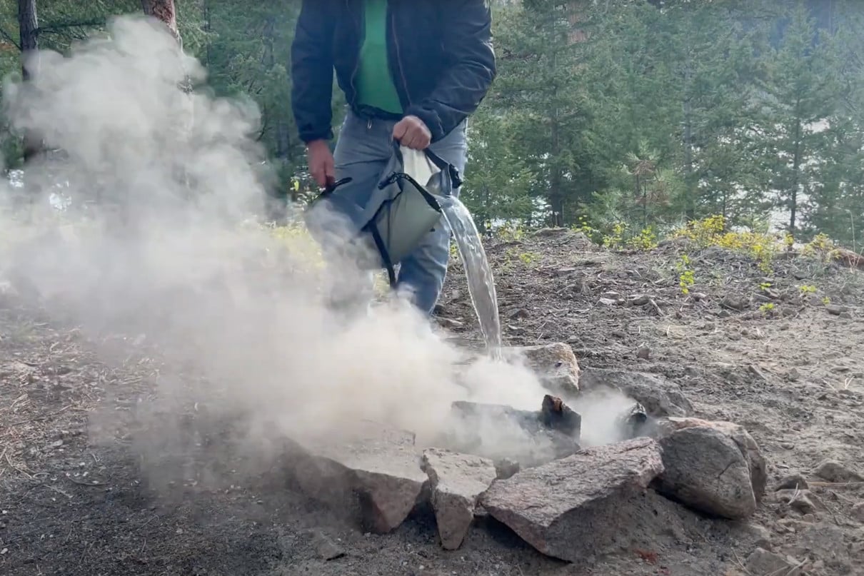 Pouring water on campfire.