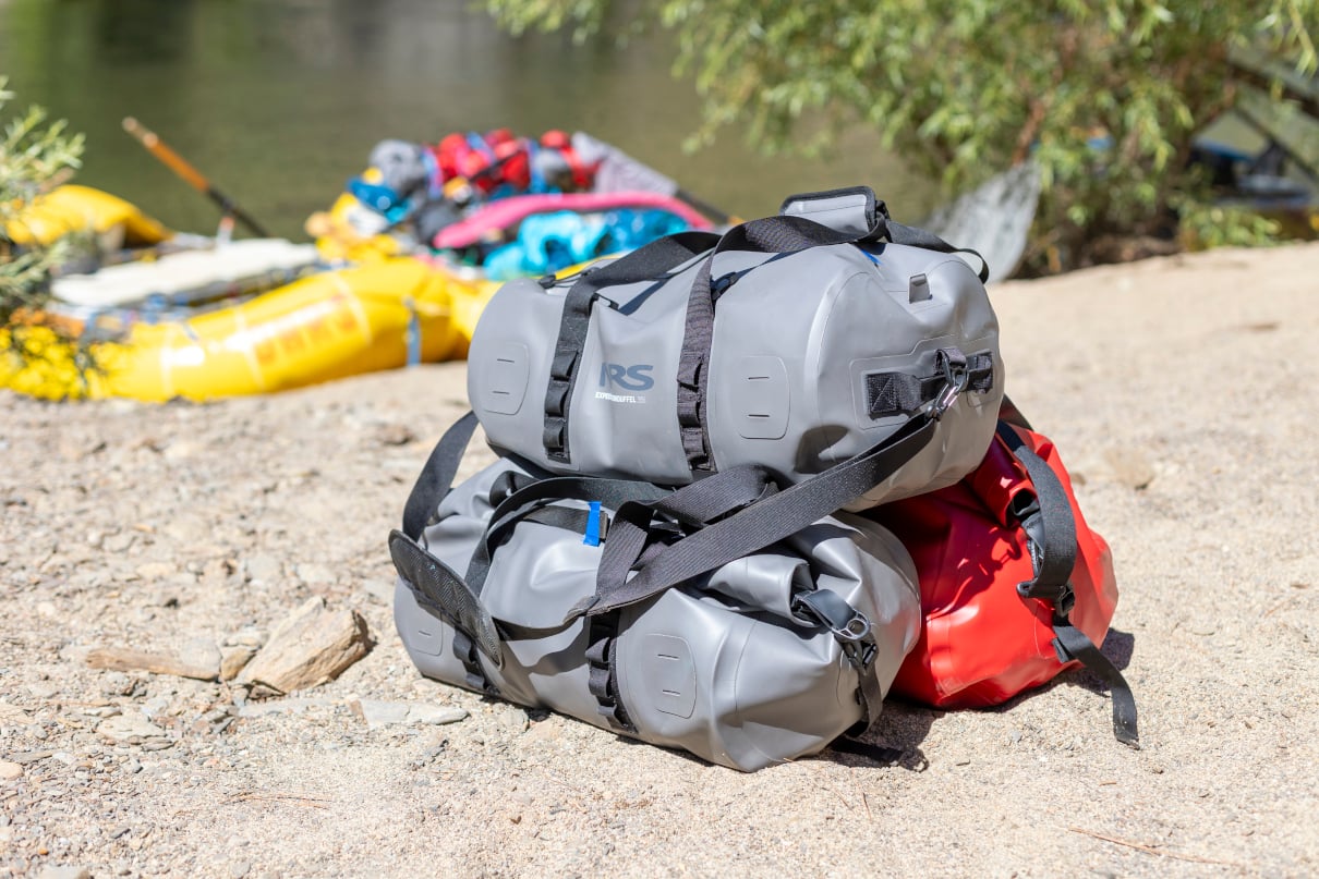 stack of NRS DriDuffels on sandy beach