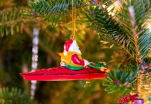 santa kayaking ornament on a christmas tree with gifts underneath