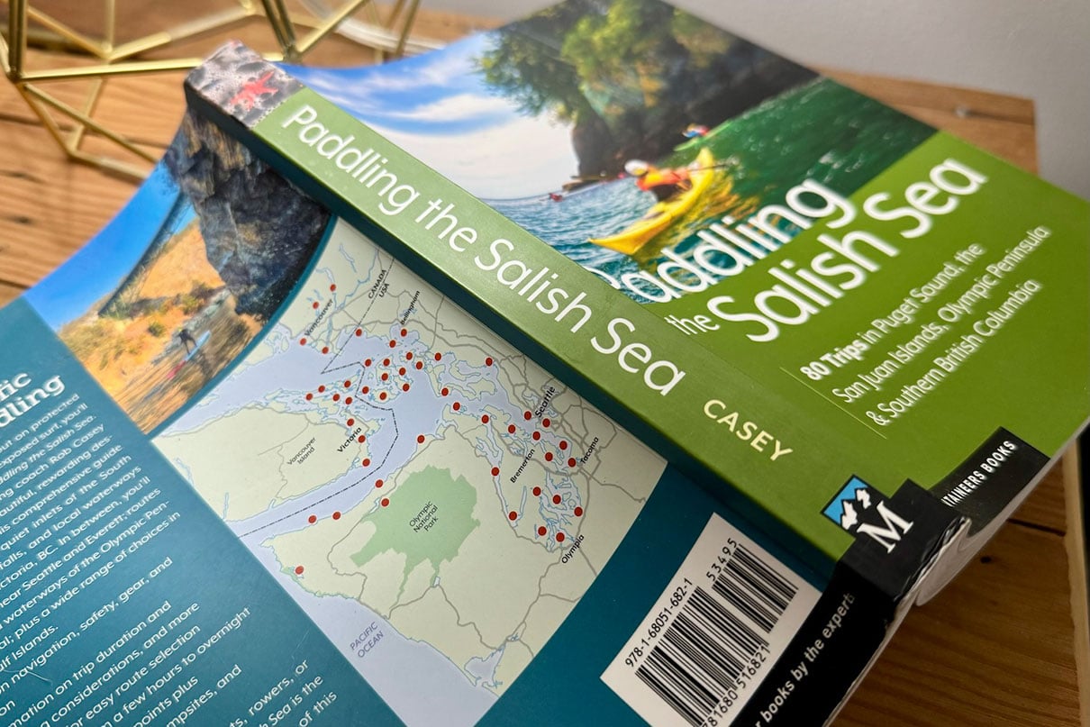 Paddling the Salish Sea guidebook sits overturned and open on a desk