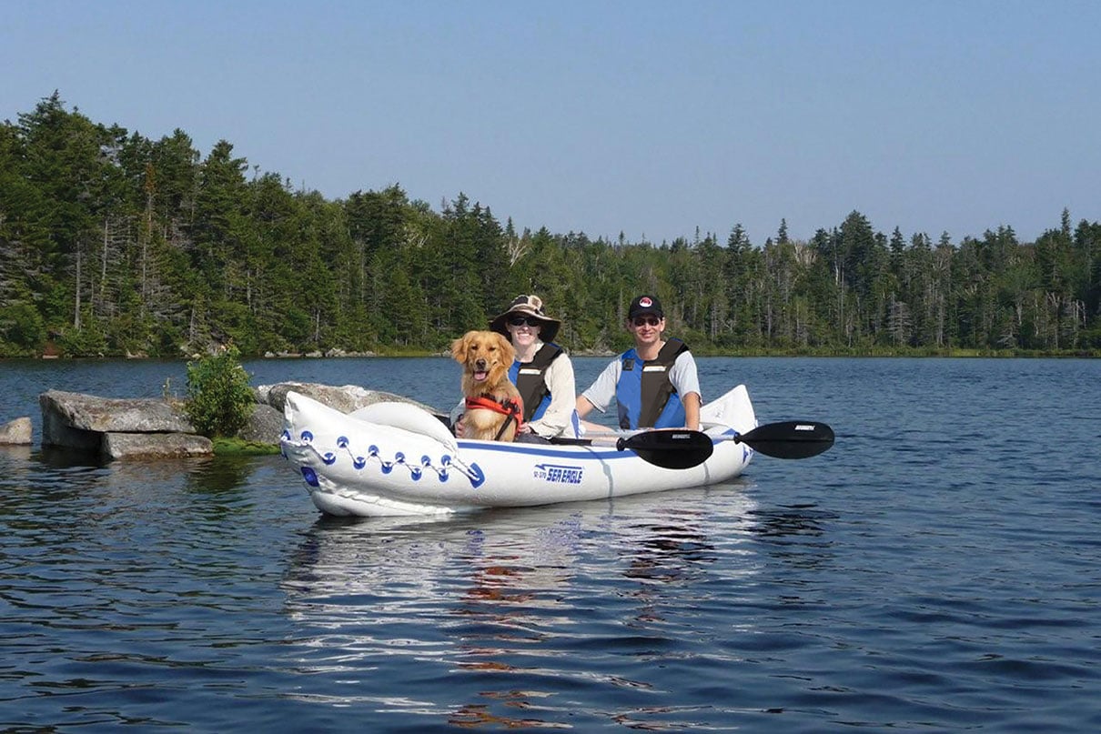 two people and dog pose in the Sea Eagle SE370 tandem inflatable kayak