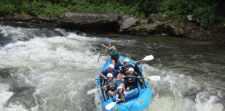 a group of rafters with guide paddle through a set of rapids