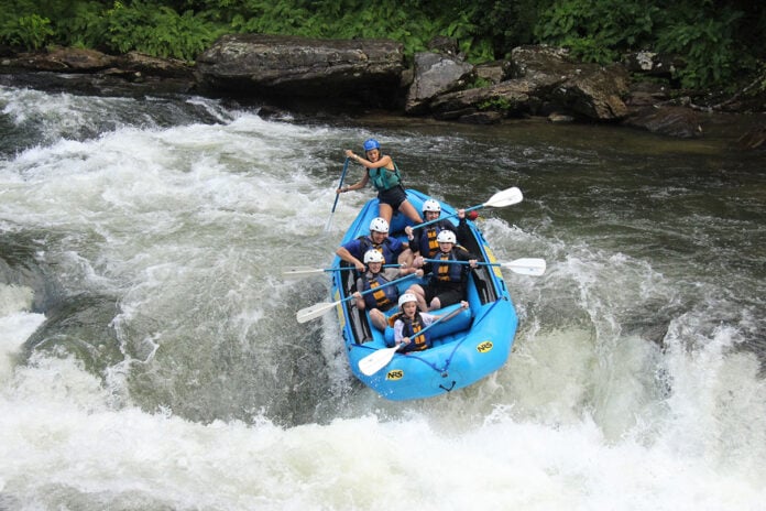 a group of rafters with guide paddle through a set of rapids