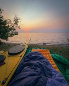 Sleeping pad and kayak in view of lake.