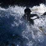 Pro Boaters On Why Expeditions Fail paddler Quinton Kennedy is silhouetted as he paddles through raging whitewater