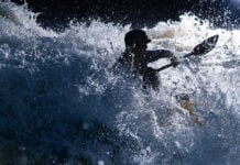 paddler Quinton Kennedy is silhouetted as he paddles through raging whitewater