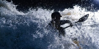 paddler Quinton Kennedy is silhouetted as he paddles through raging whitewater