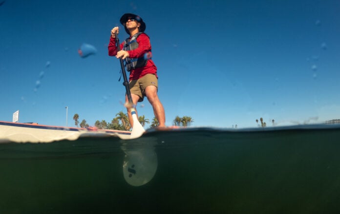 Man on paddleboard seen from water level.