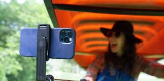 woman smiles at her phone held on a selfie stick while portaging a canoe