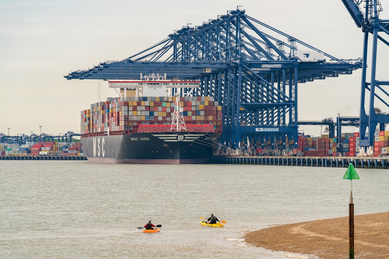 Kayaks paddling near cargo ship and port of trade.