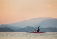 woman paddles the Eddyline Caribbean 10 kayak under rosy skies