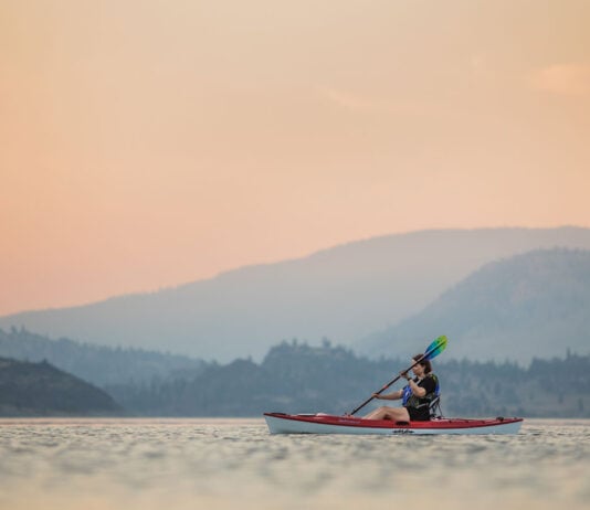 woman paddles the Eddyline Caribbean 10 kayak under rosy skies