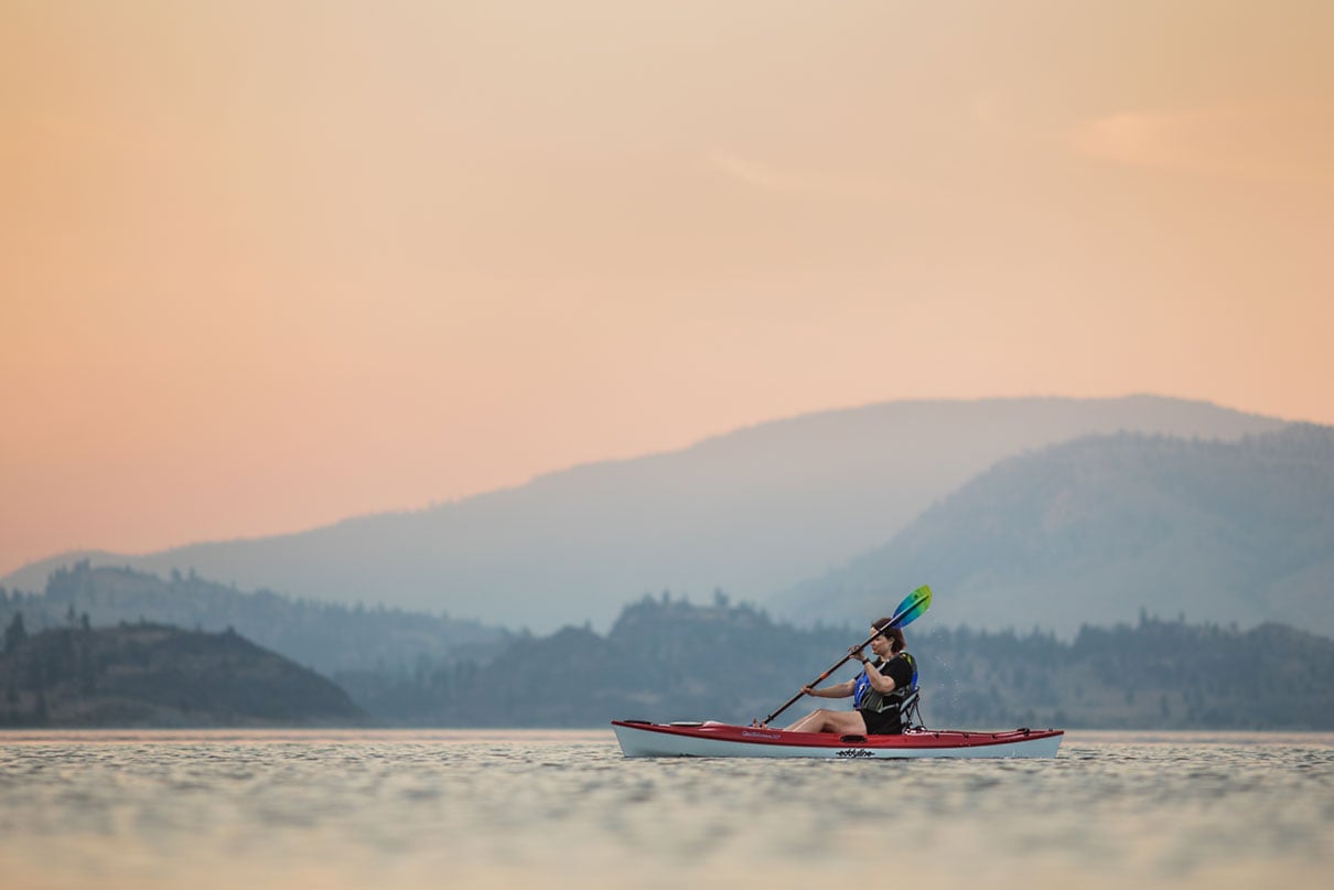 woman paddles the Eddyline Caribbean 10 kayak under rosy skies