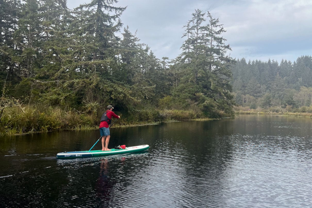 person paddles the Red Voyager inflatable paddleboard