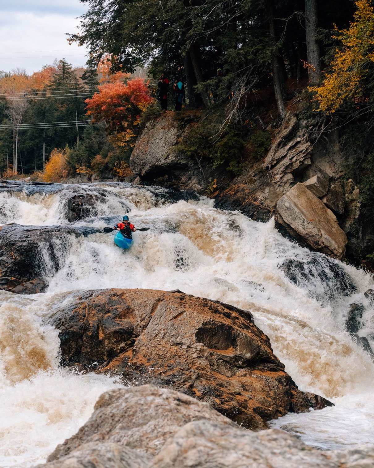 kayaker paddles through a Class V+ waterfall