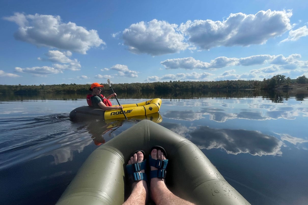 bow shot of a packraft with person wearing Astral Webber water shoes