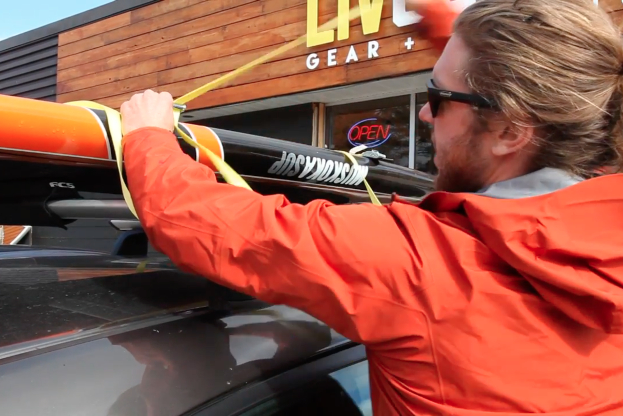 Tightening cam strap over paddleboard.