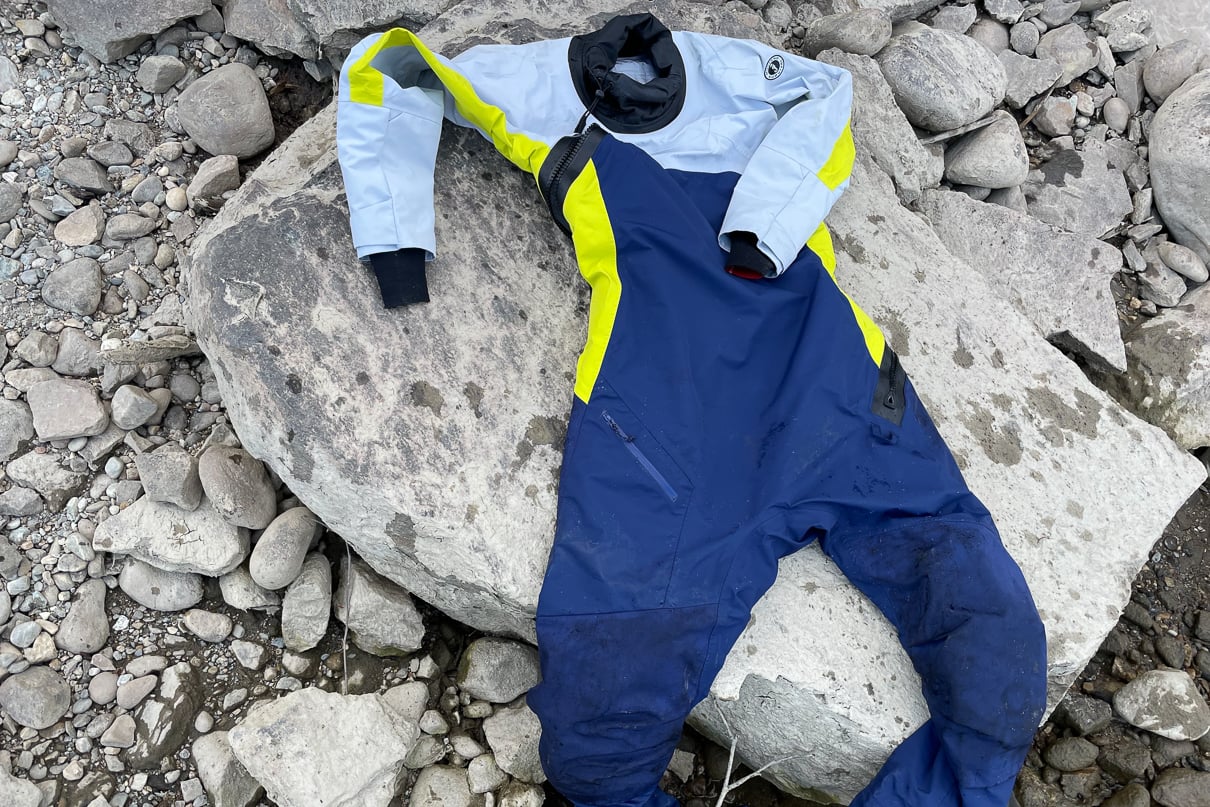Image of the Helix Women's Drysuit by Mustang Survival on rocks by a river