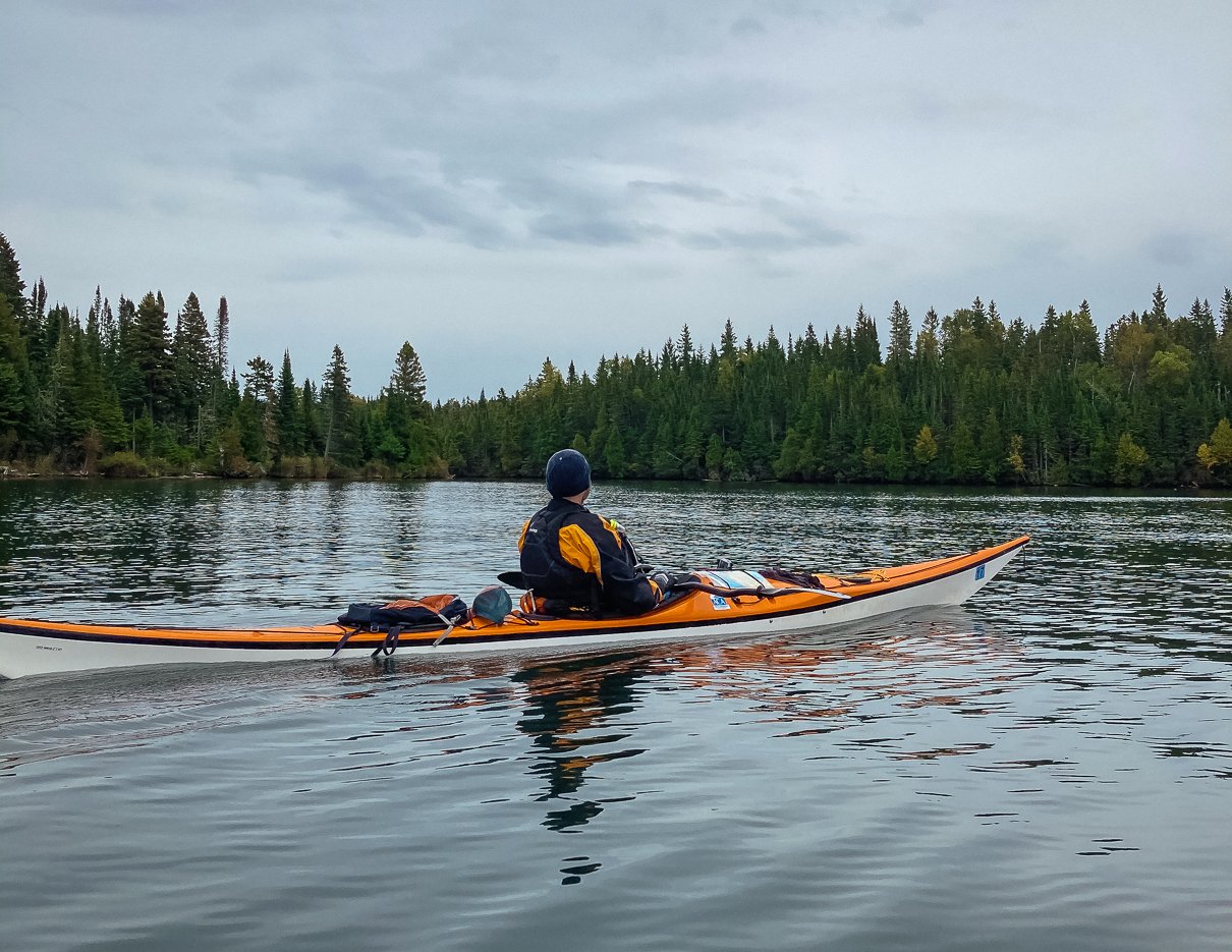 Image of a sea kayaker in the water with kayak registration decal visible above the waterline